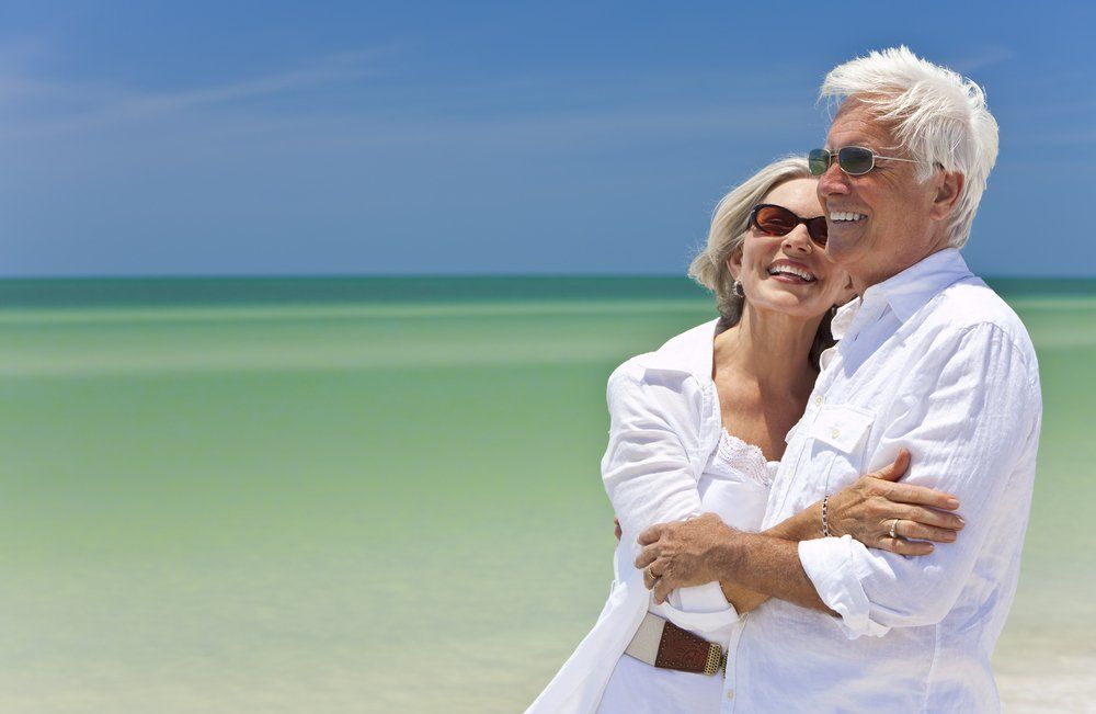 Man and Woman Smiling in Front of Beach — Dentists in Nelson Bay, NSW