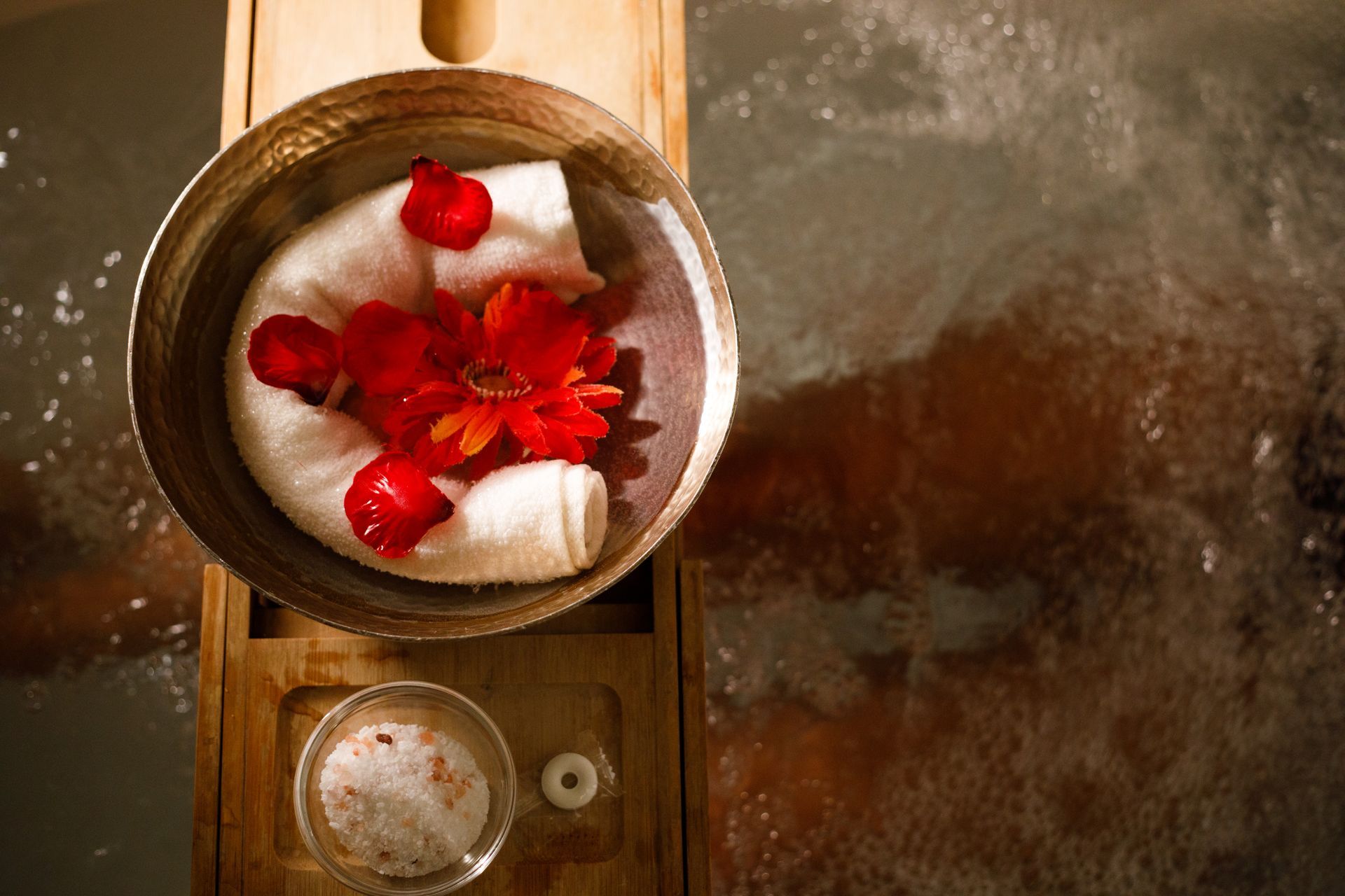 A bowl of rose petals over a soaking tub