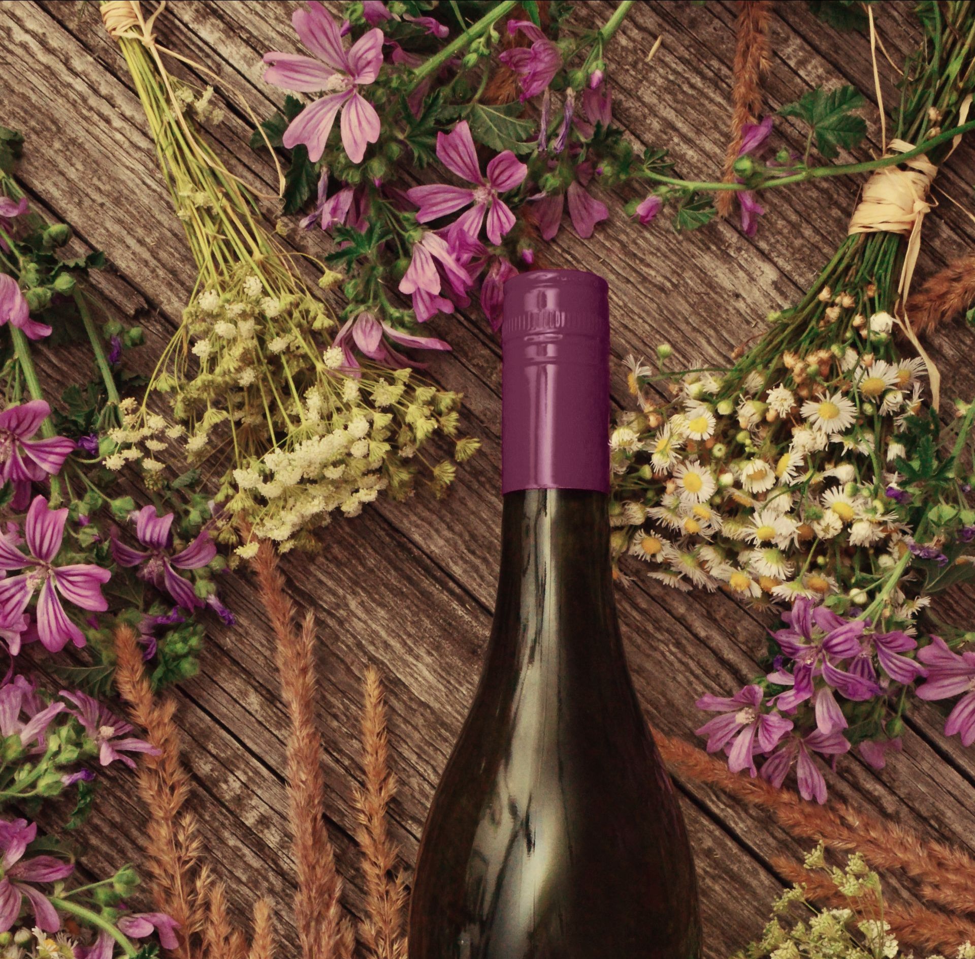 A bottle of wine with herbs and flowers