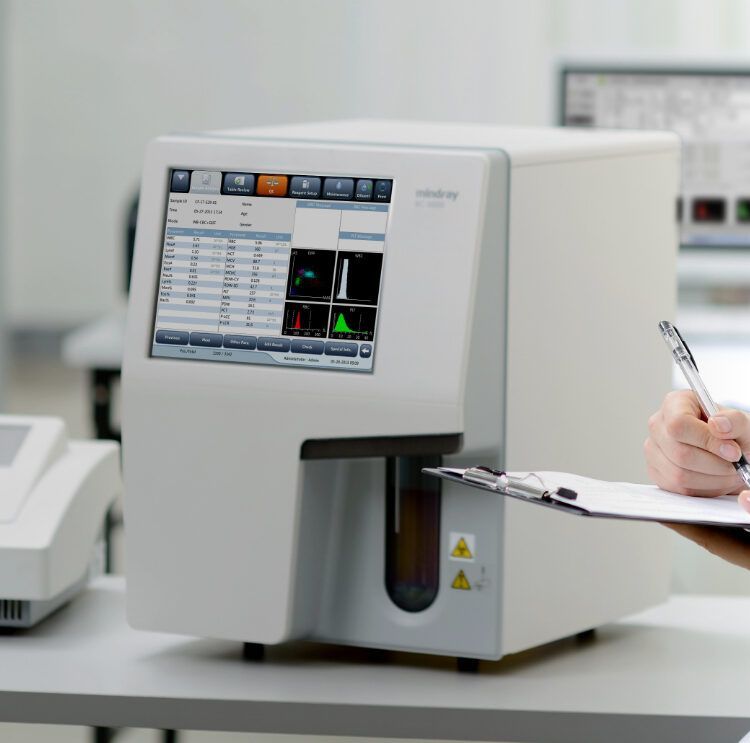 Manos enguantadas colocando una tira reactiva en un analizador de laboratorio con pantalla digital.