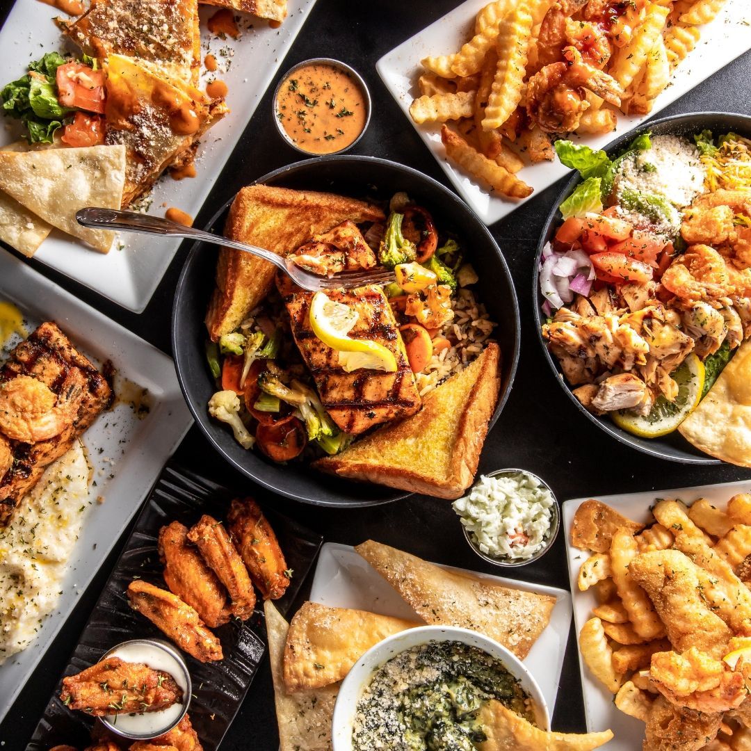 Overhead view of a table laden with a variety of dishes including seafood, fried chicken, sides, and dips.