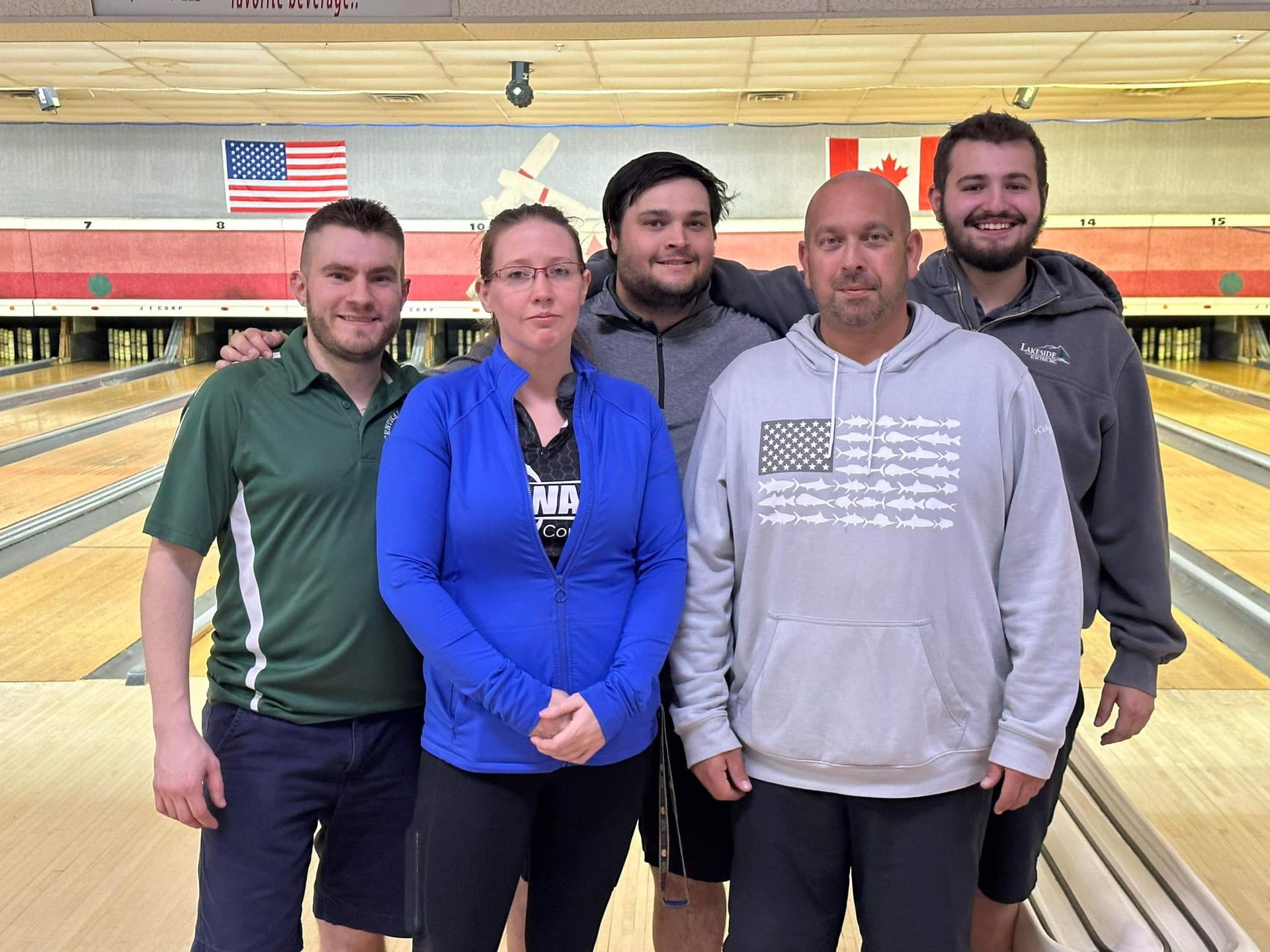 A group of people are posing for a picture at a bowling alley.