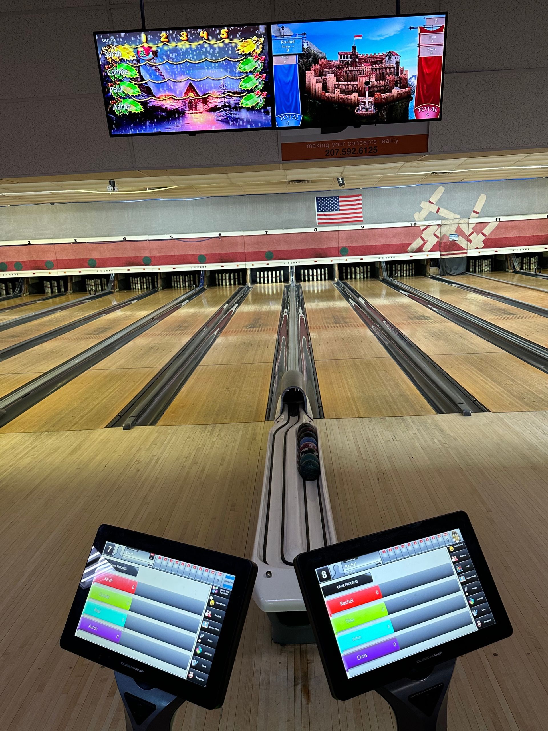 A bowling alley with two monitors on the side of the bowling alley
