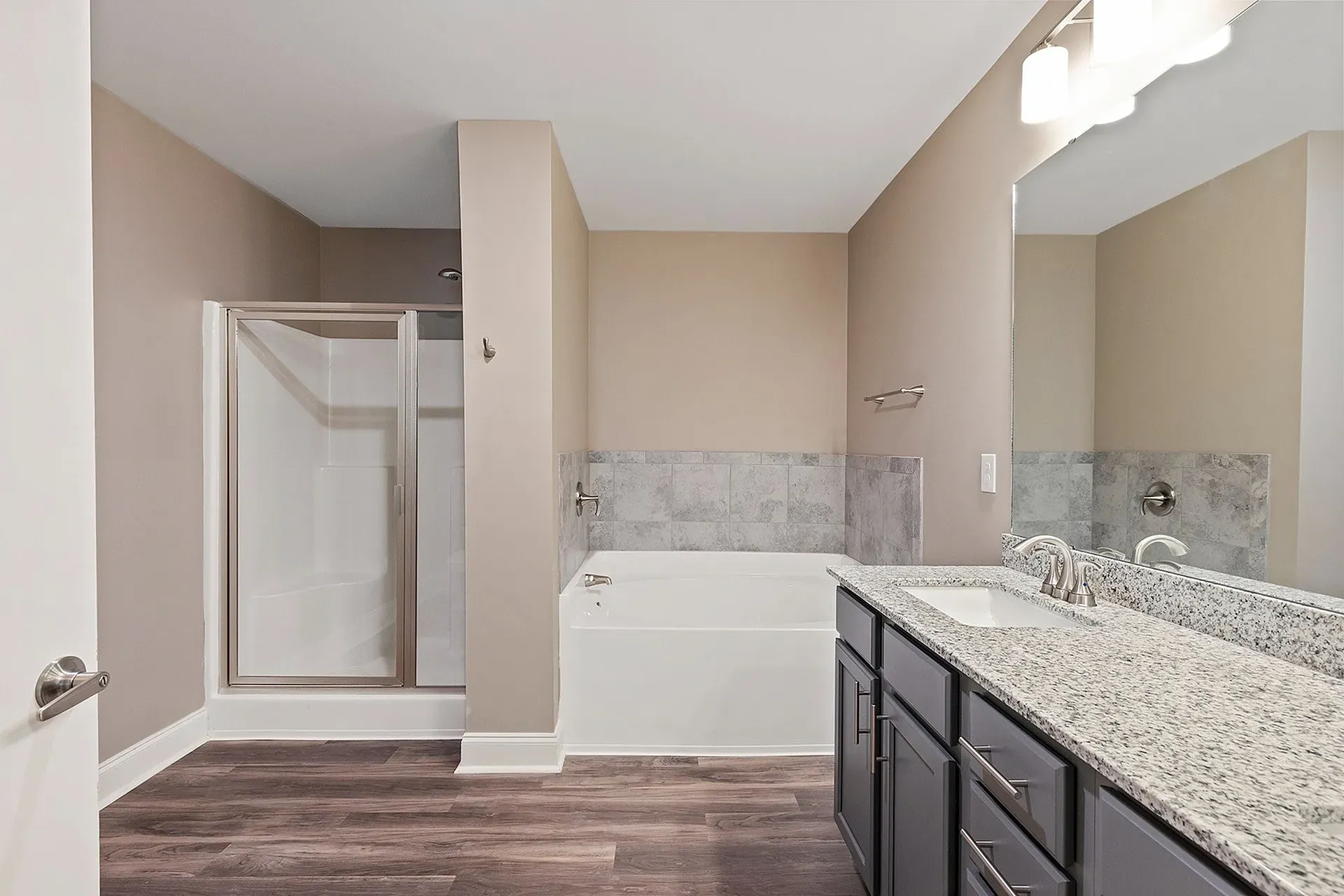 Bathroom with tub/shower, tile surround, and granite vanity in a modern apartment.