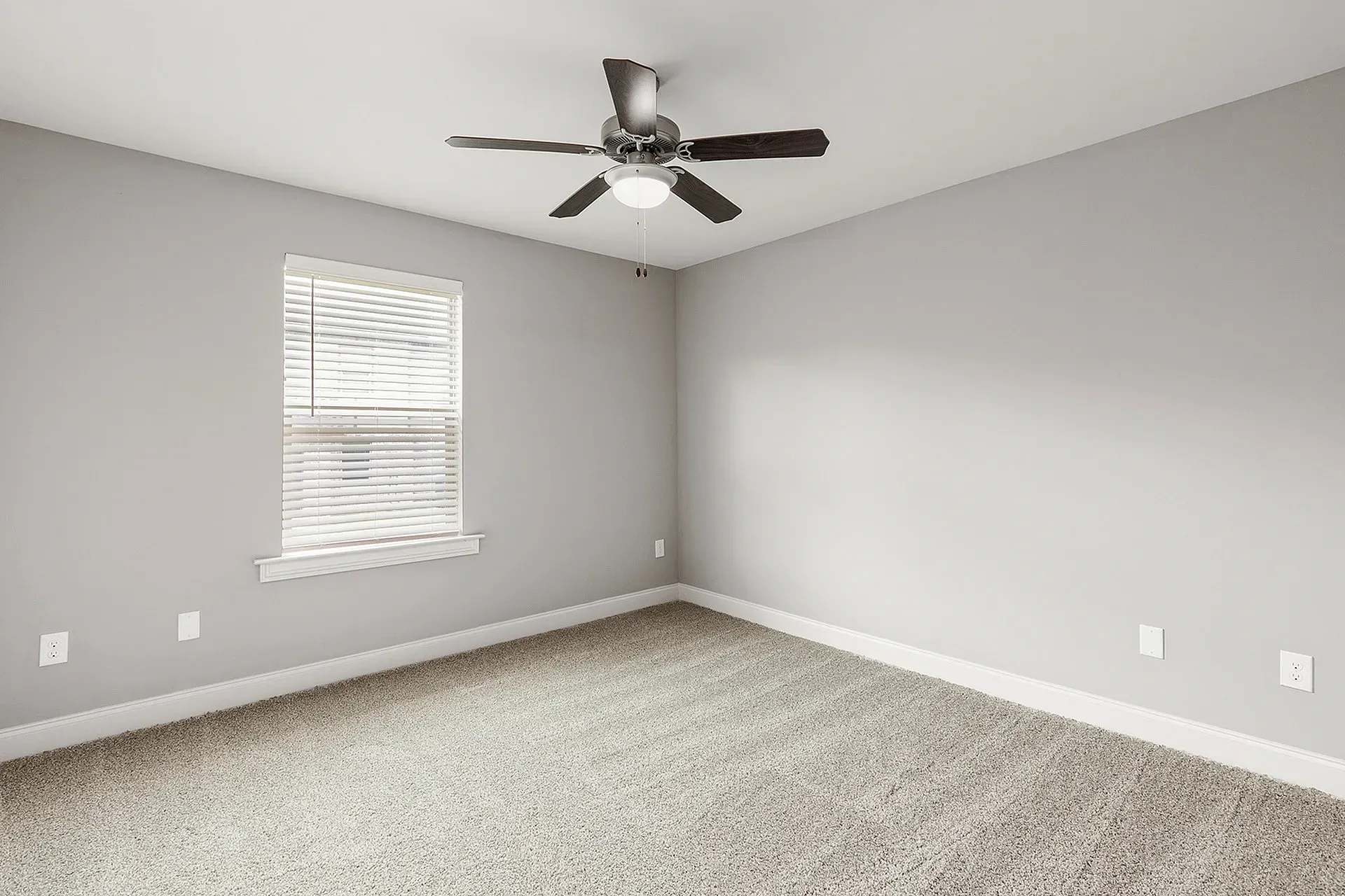 Empty gray bedroom with window, blinds, and ceiling fan.
