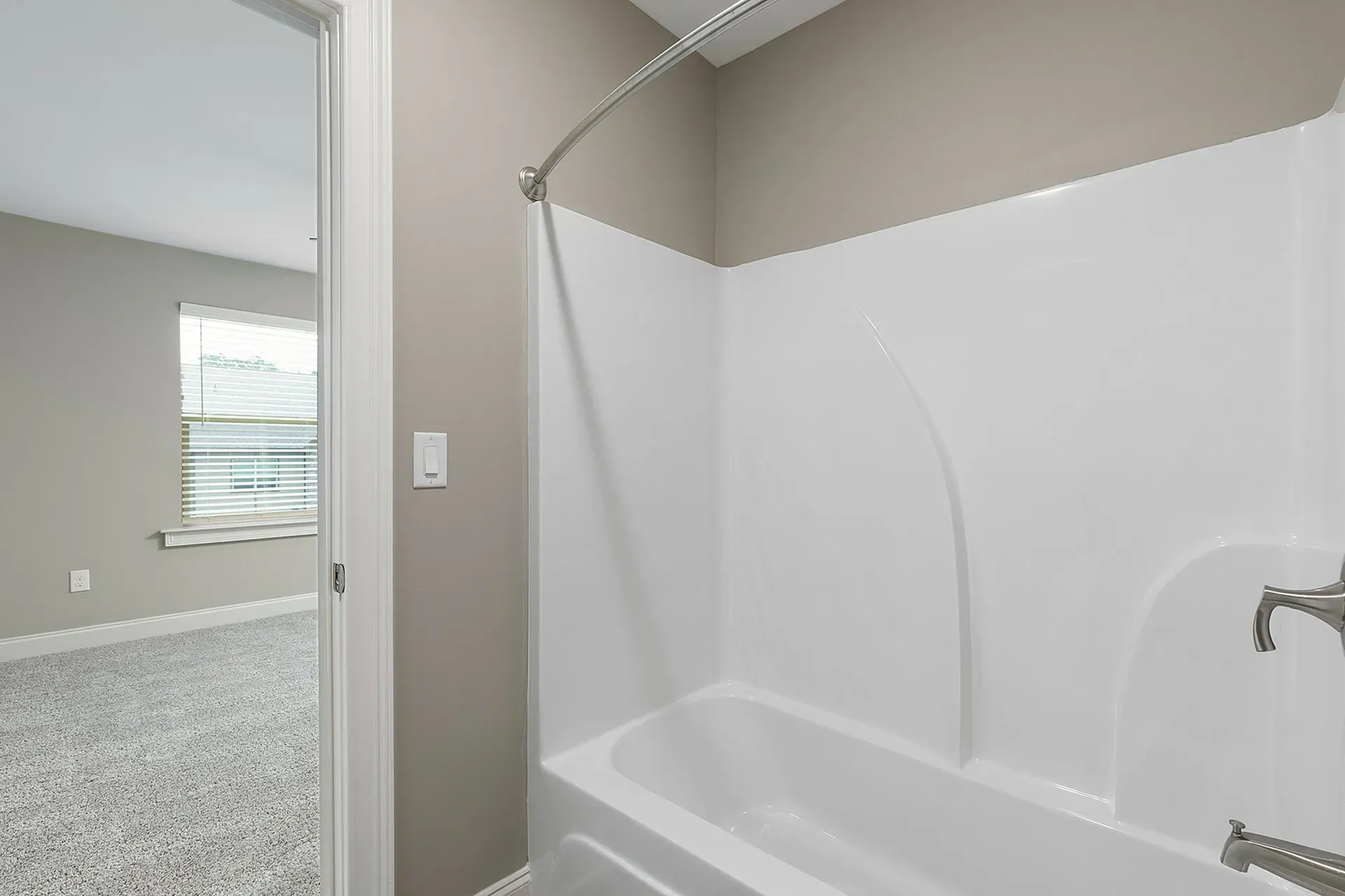 Bathroom with white tub/shower surround and curved shower rod.
