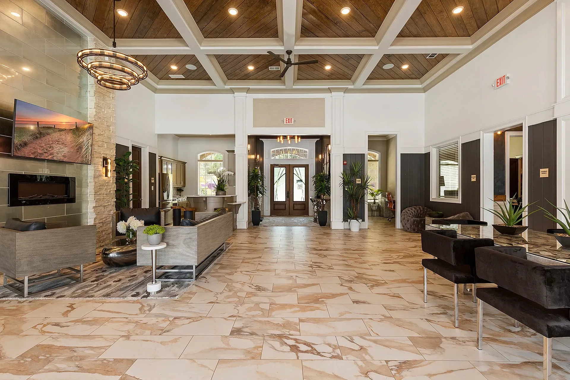 Open lobby with seating area, stone fireplace, plants, and double doors at the entrance.