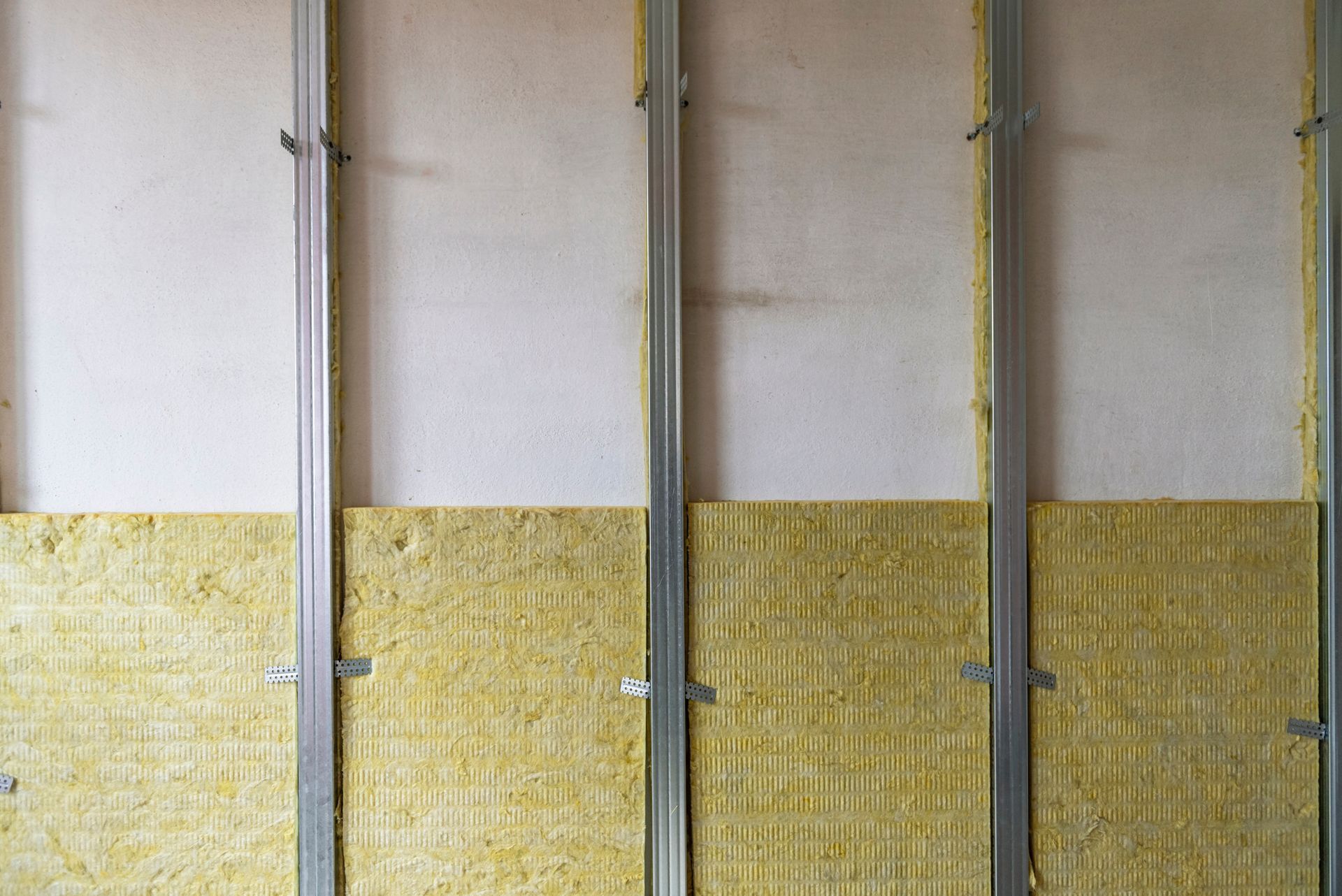 Close-up of a wall with yellow insulation panels and vertical metal studs.