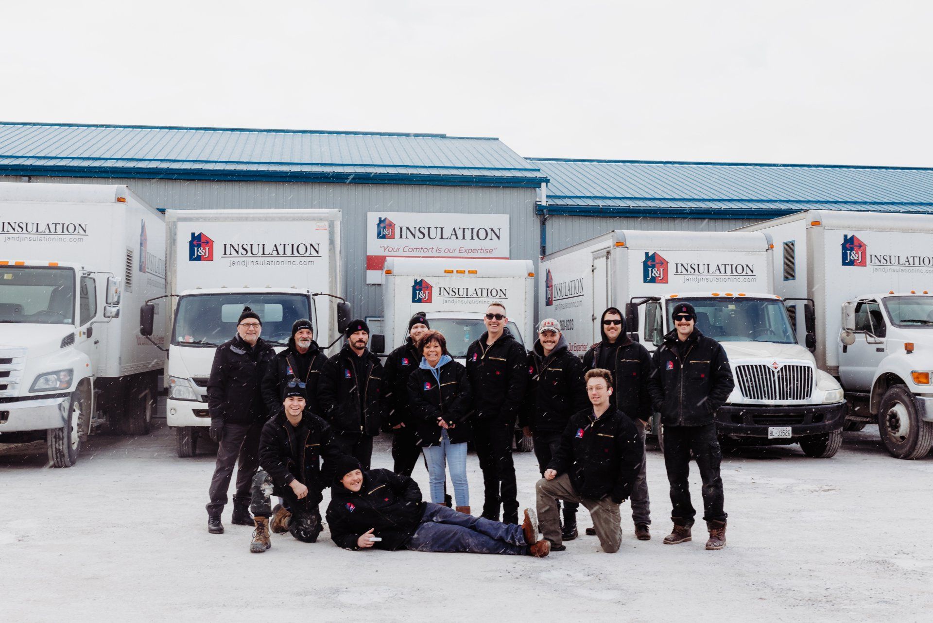 Group of people posing in front of delivery trucks in a snowy lot