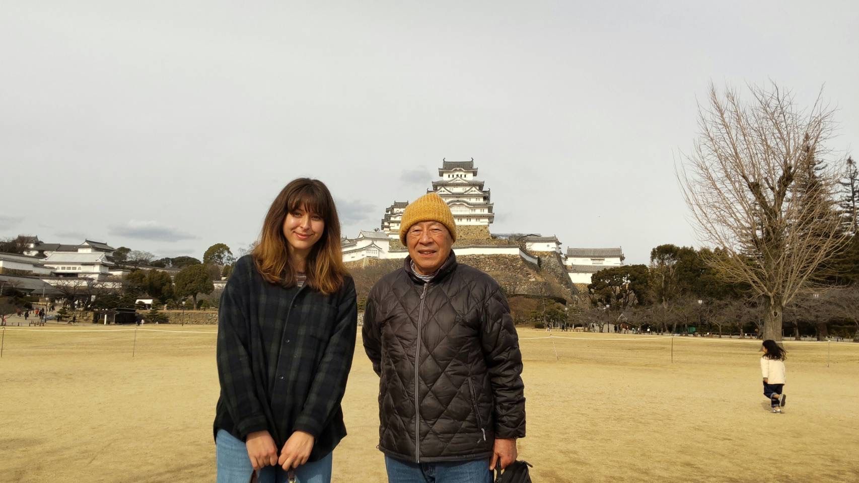 Two people standing in a field with a castle in the background on a clear day