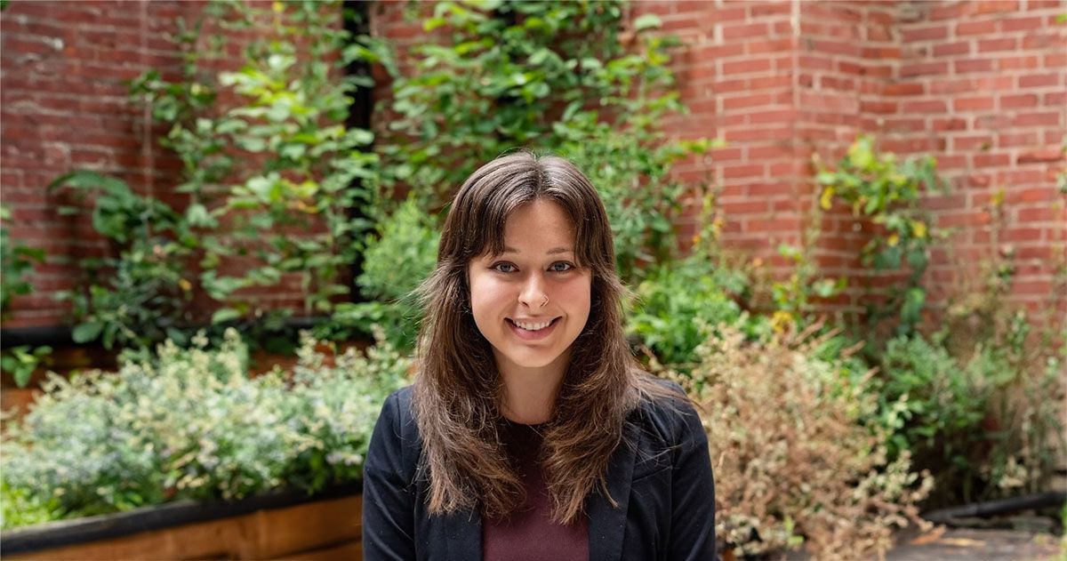 Natalie Montecino Standing in front of garden and brick wall