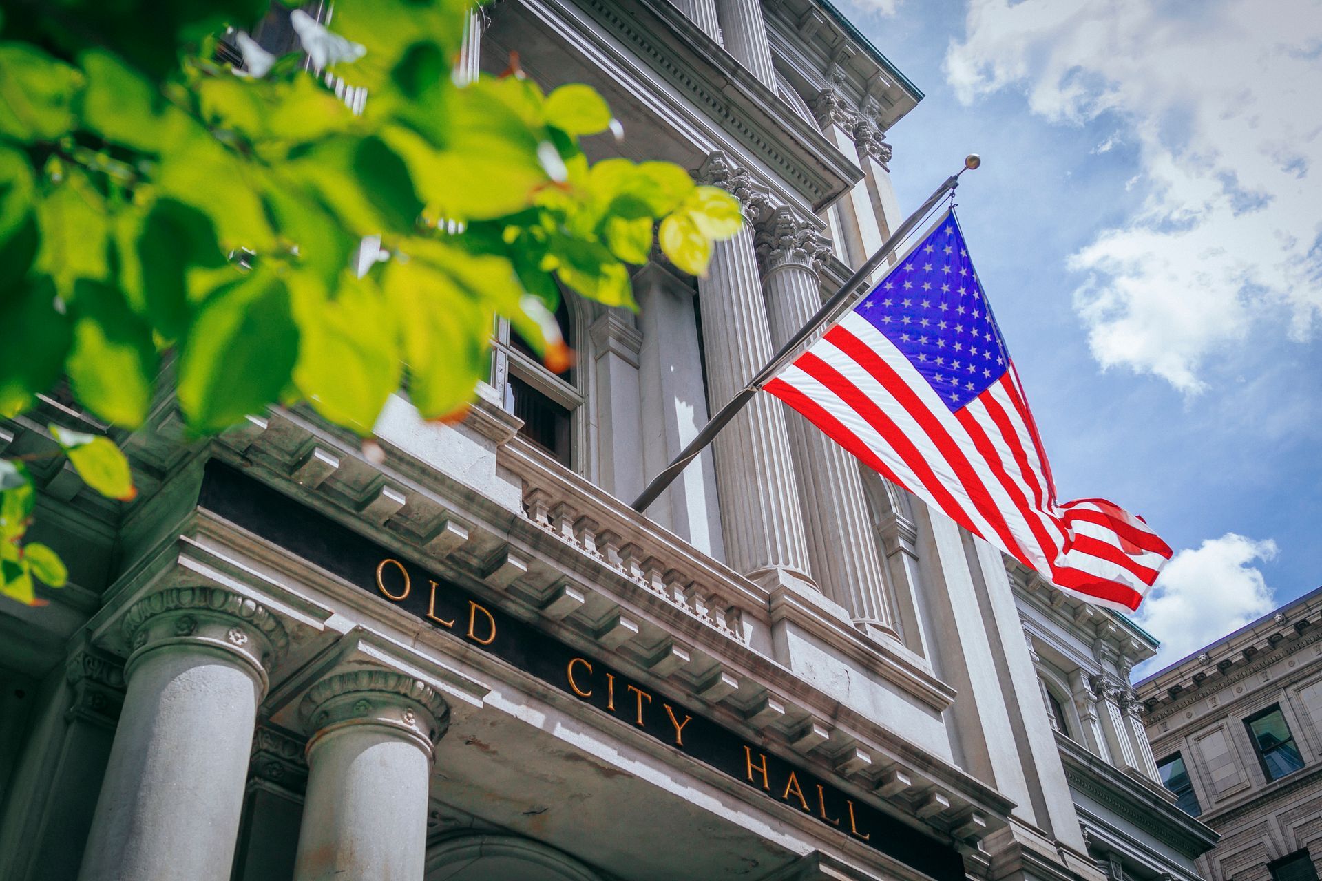 Old City Hall facade with U.S. flag flying against a blue sky