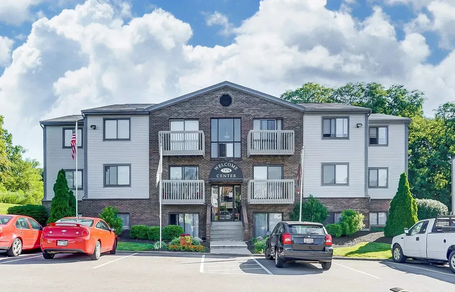 Apartment building exterior with parked cars and a bright blue sky