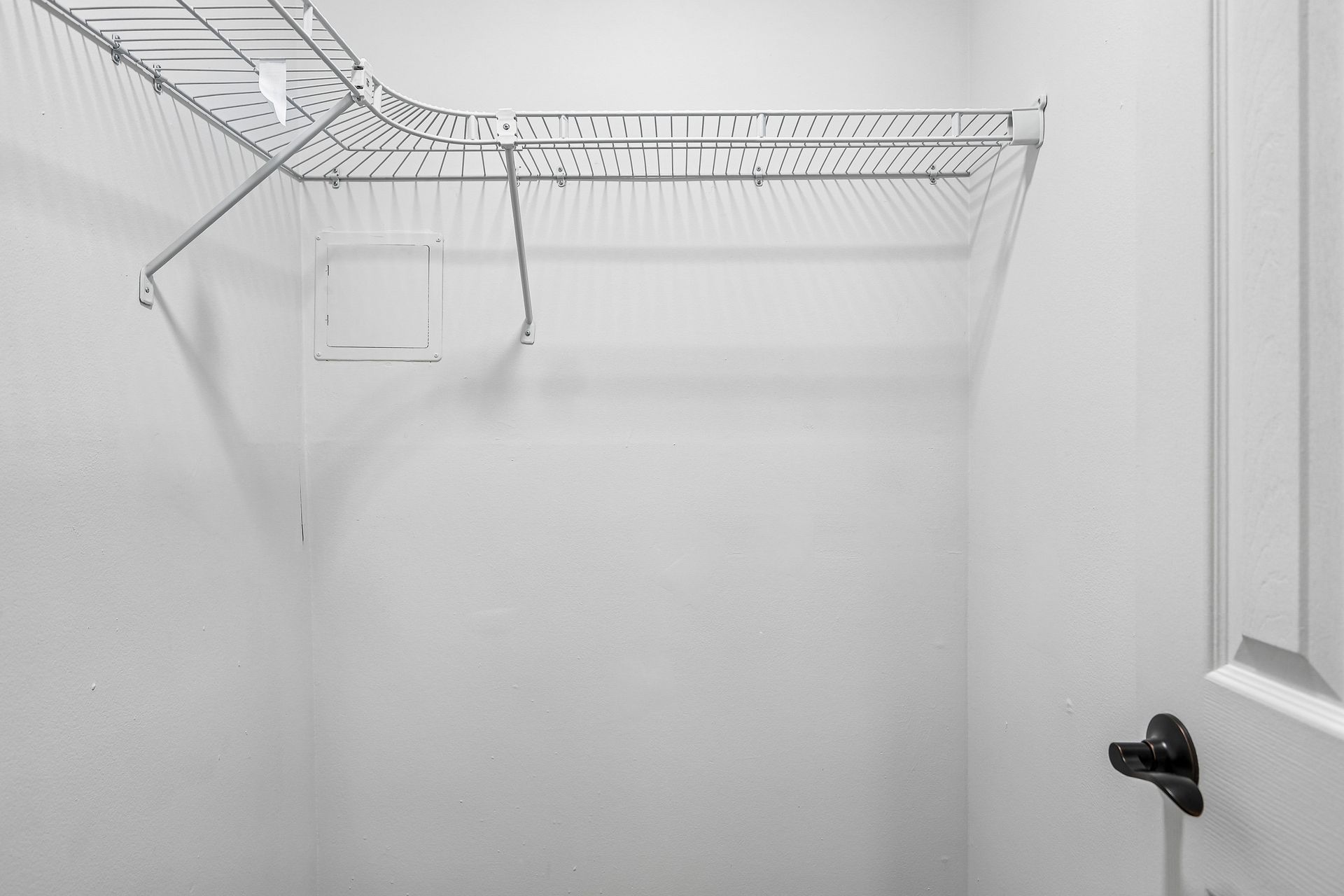 Empty white closet with wire shelving and a hanging rod, viewed from the doorway