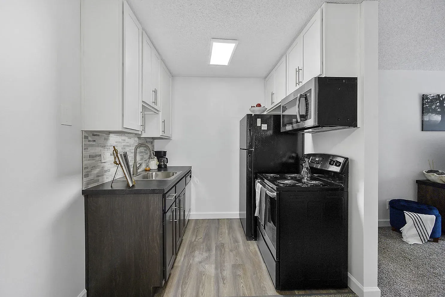 Tall Timber Apartments kitchen with white upper cabinets, dark lower cabinets, stainless-steel appliances, and a double sink.