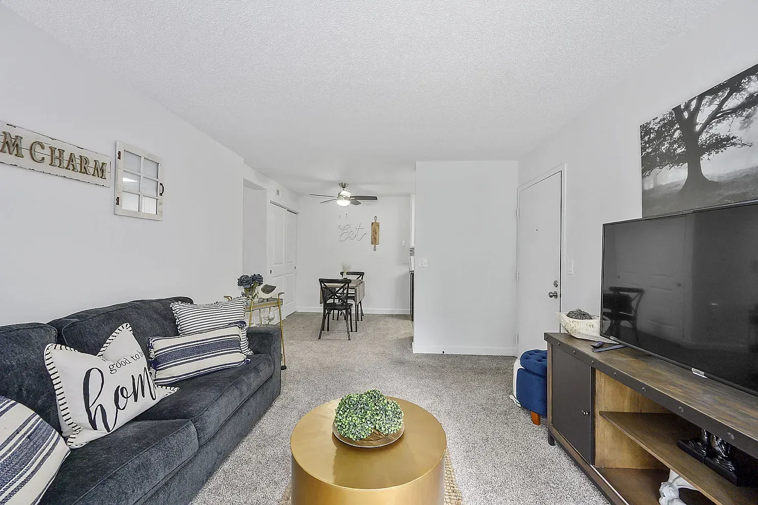 Tall Timber Apartments living room in an apartment with a dark sofa, striped pillows, a coffee table, and a TV.