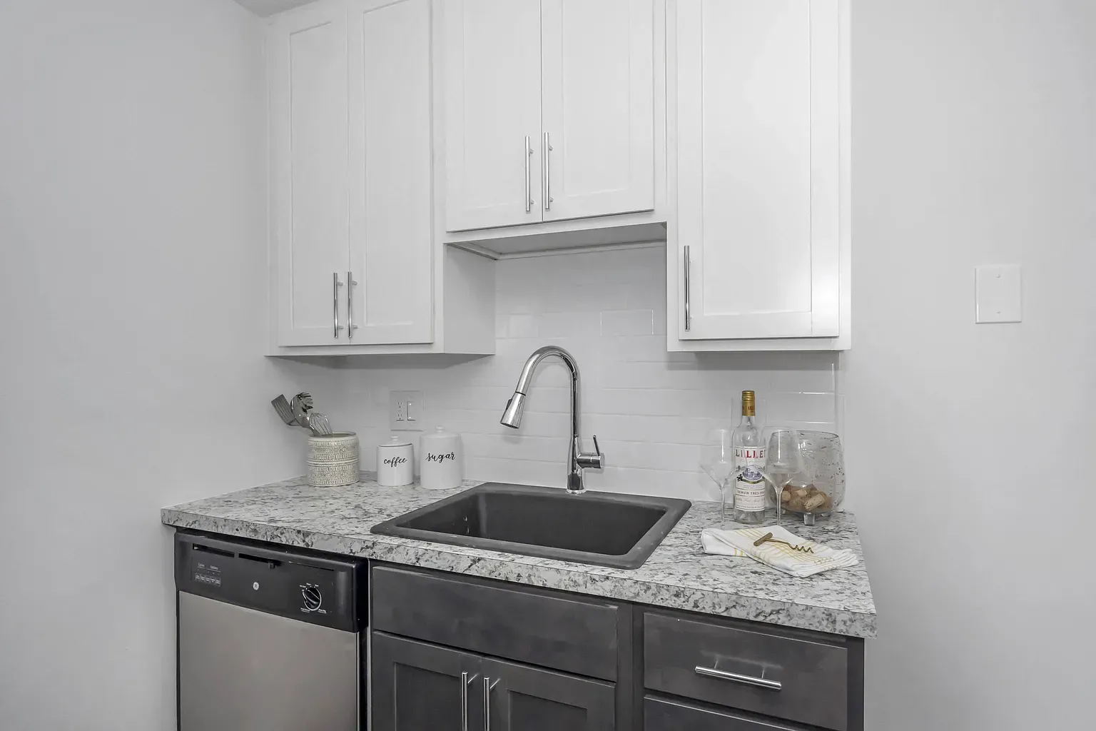 Tall Timber Apartments kitchen with white cabinets, granite countertop, and stainless steel sink.