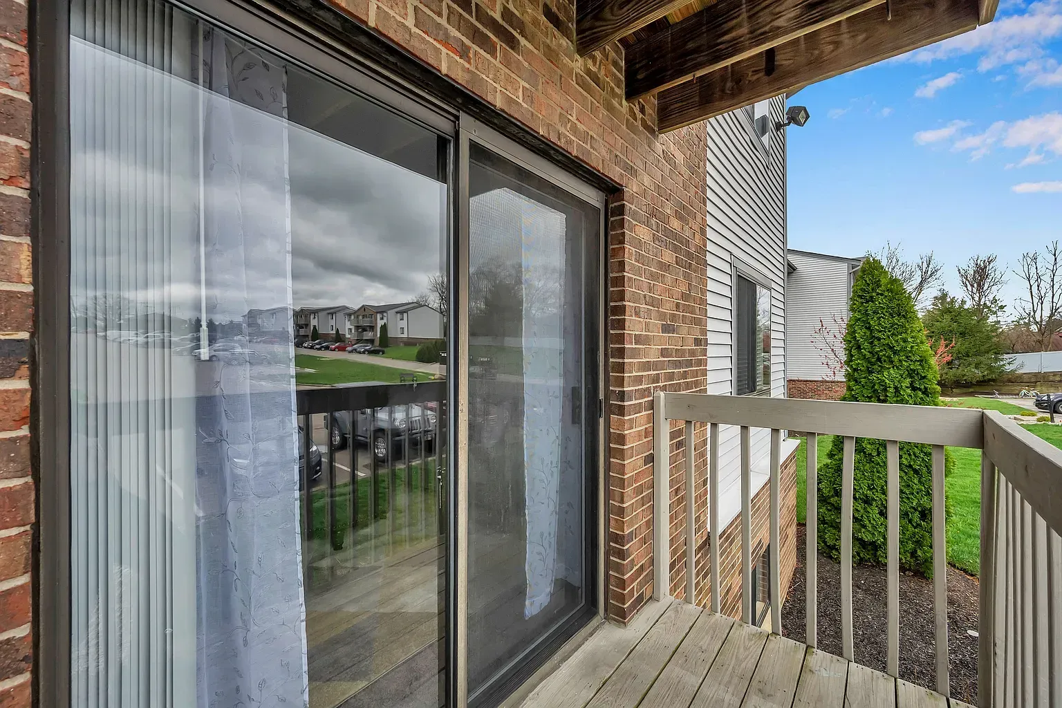 Tall Timber Apartments Balcony view from an apartment unit with sliding glass doors and brick exterior.
