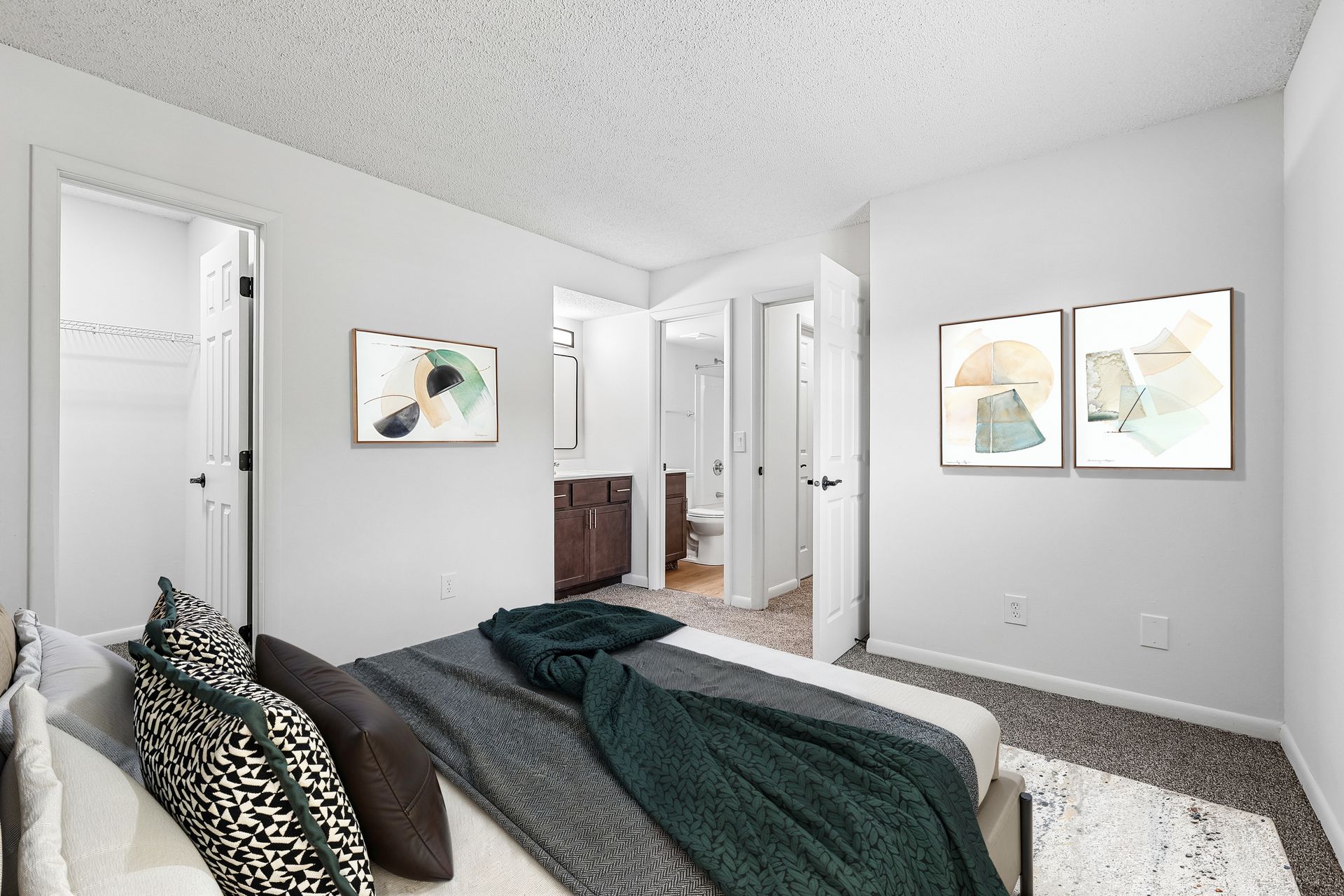 Tall Timber Apartments Minimalist bedroom with gray walls, bed, wall art, and open doors to hallway and bathroom