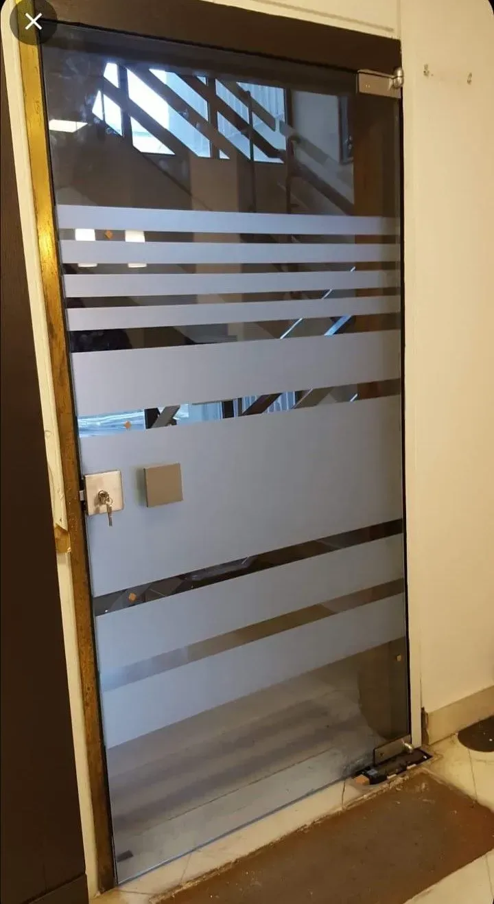 Porta a vetri con strisce orizzontali satinate all'ingresso del corridoio.