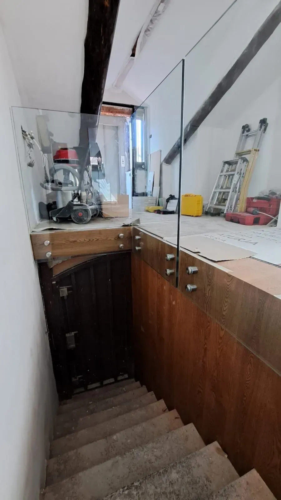 Una stretta scala accanto a un bancone di legno, con gradini che conducono a un piccolo spazio interno.