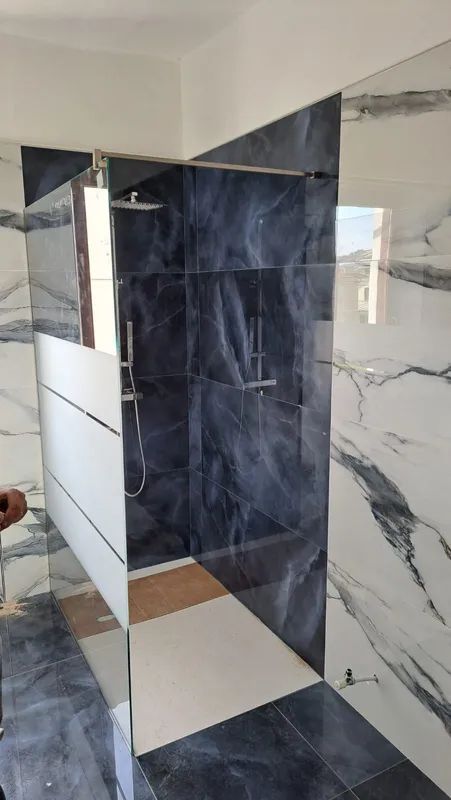 Bagno moderno con piastrelle effetto marmo blu navy e bianche e box doccia in vetro.