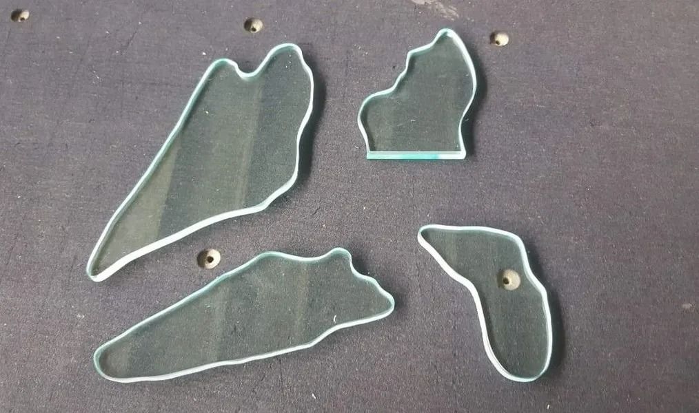 Quattro pezzi di puzzle in plastica trasparente su una superficie grigia, con contorno bianco.