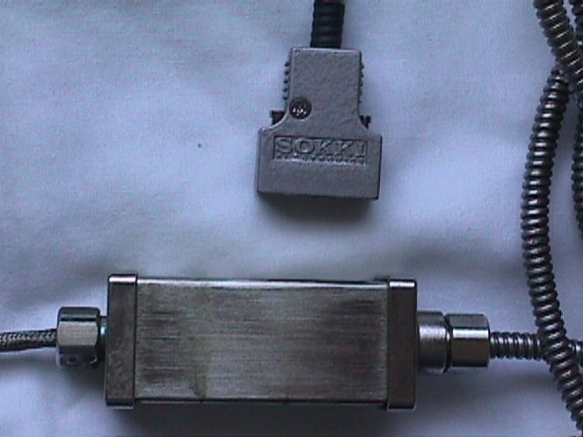 Gray sensor or connector box with coiled cable on a light background