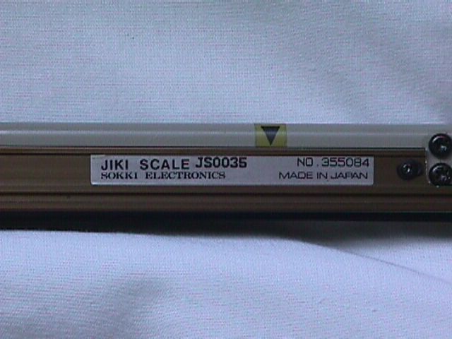 Close-up of a JIKI electronic scale label on a beige metal device with black screws.