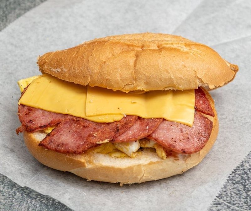 A sandwich with ham cheese and eggs on a bun
