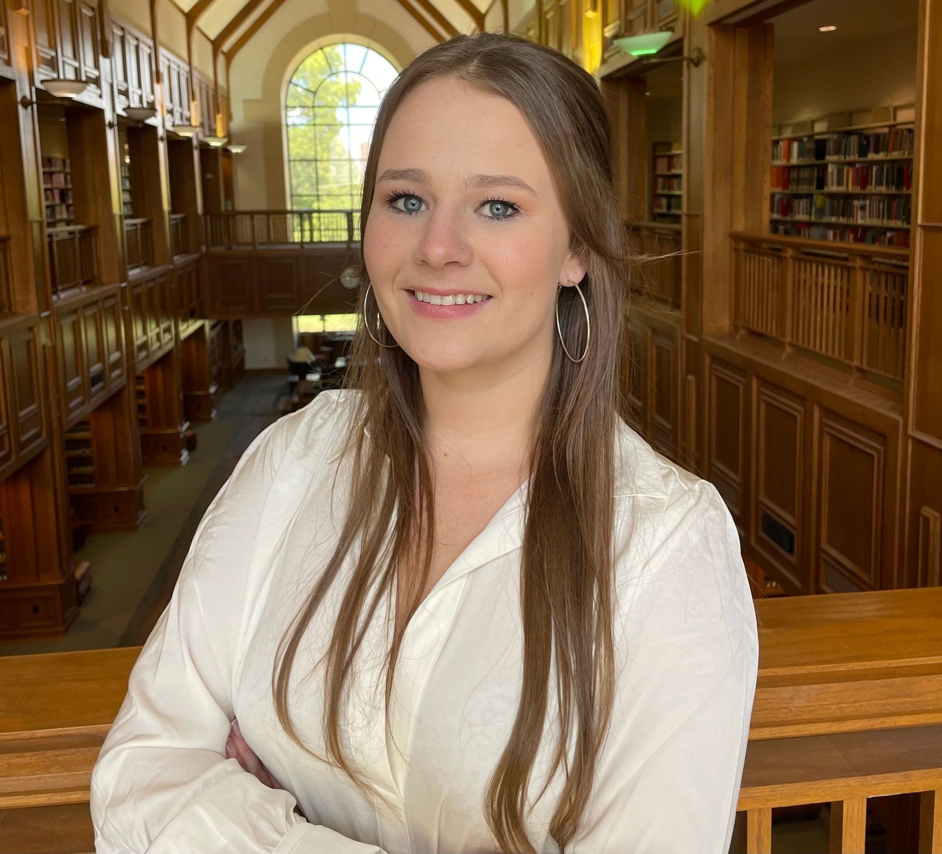 A woman in a white shirt is smiling in a library