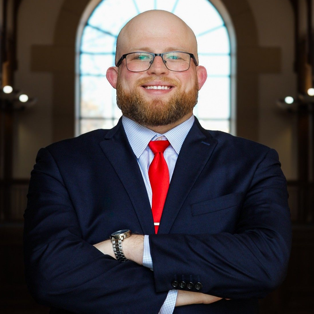 A man with a beard is wearing a suit and tie and smiling.