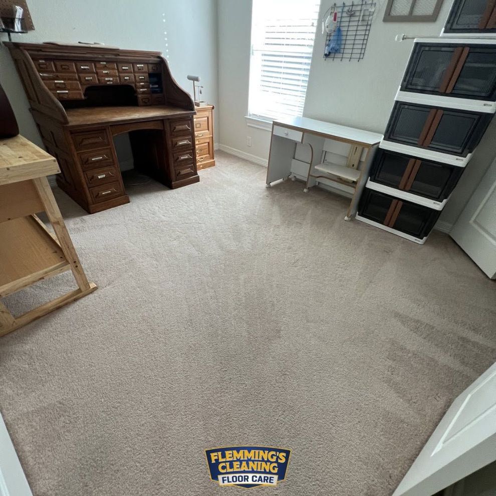 Carpeted room with a wooden roll-top desk, white table, and shelves against the wall.