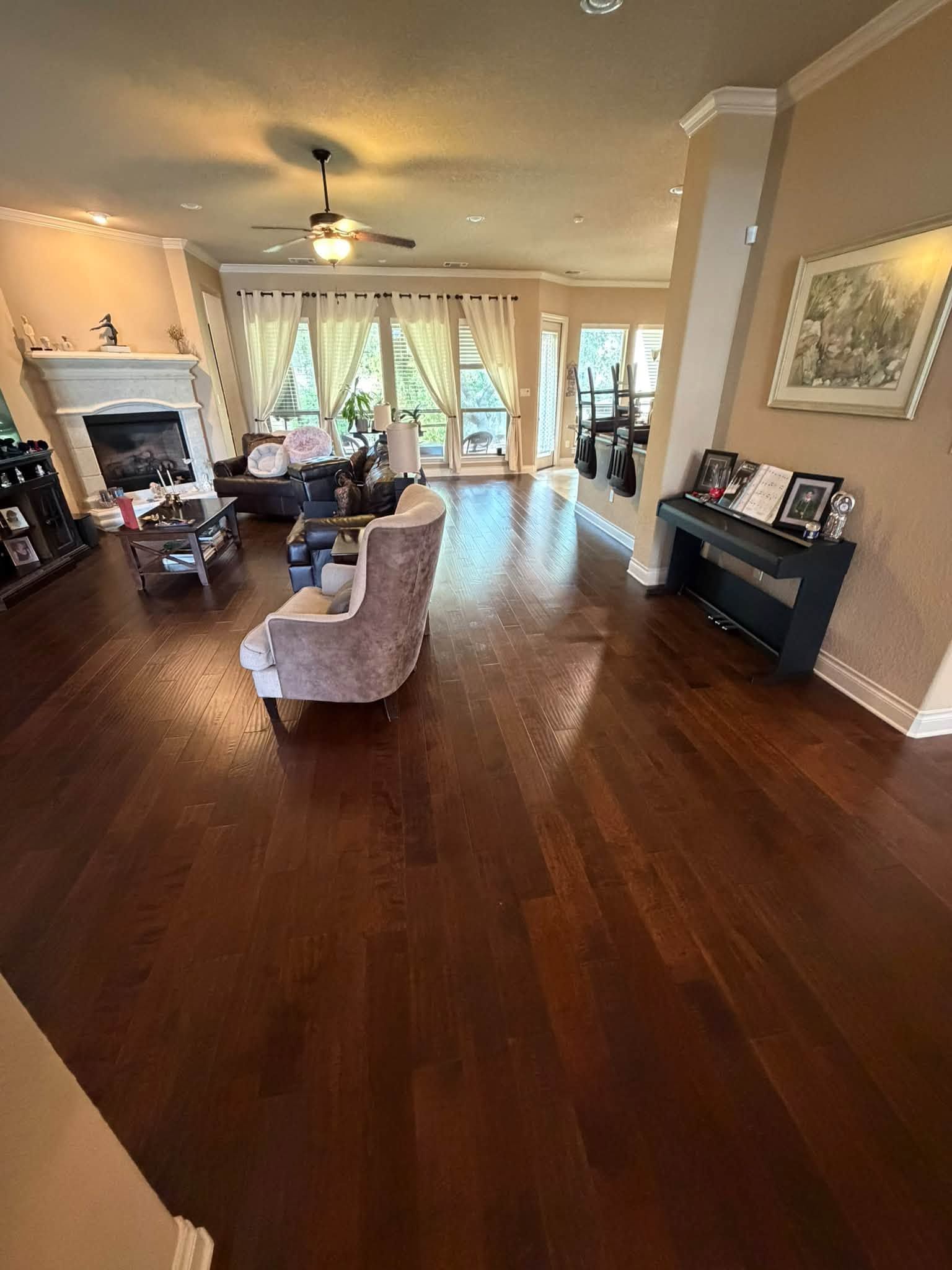 Spacious living room with dark wood floors, a fireplace, armchairs, and sliding glass doors to a bright patio.