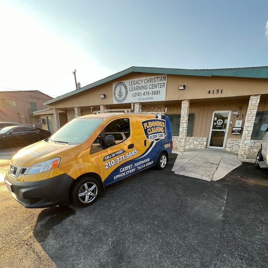 Yellow-and-blue service van parked outside a chiropractic office with stone pillars and a ramp.