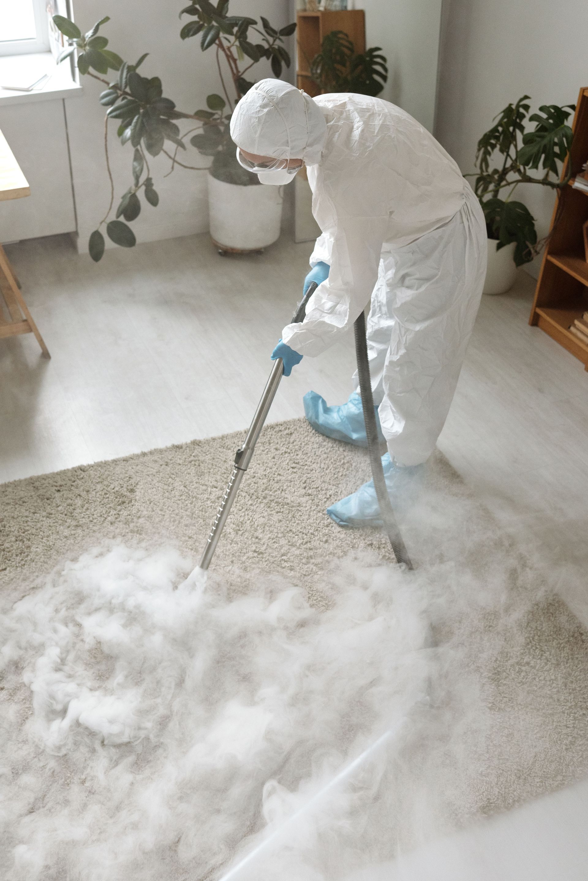Person in white protective suit spraying foam cleaner on a living room rug