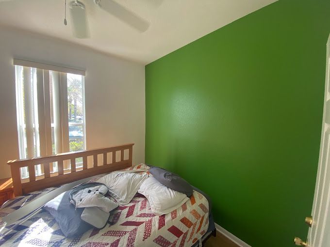 A bedroom with a bed and a green wall.