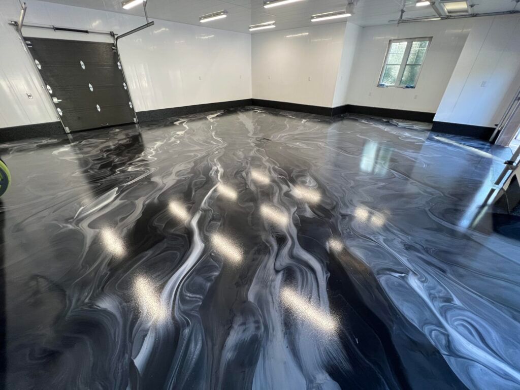Empty garage with glossy black floor coating and overhead lights reflected on the surface
