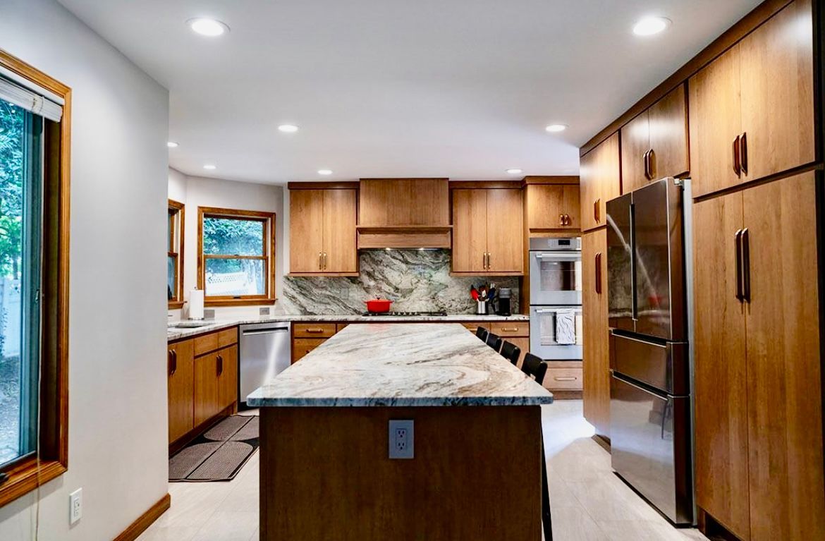 A kitchen with wooden cabinets , stainless steel appliances , and a large island.