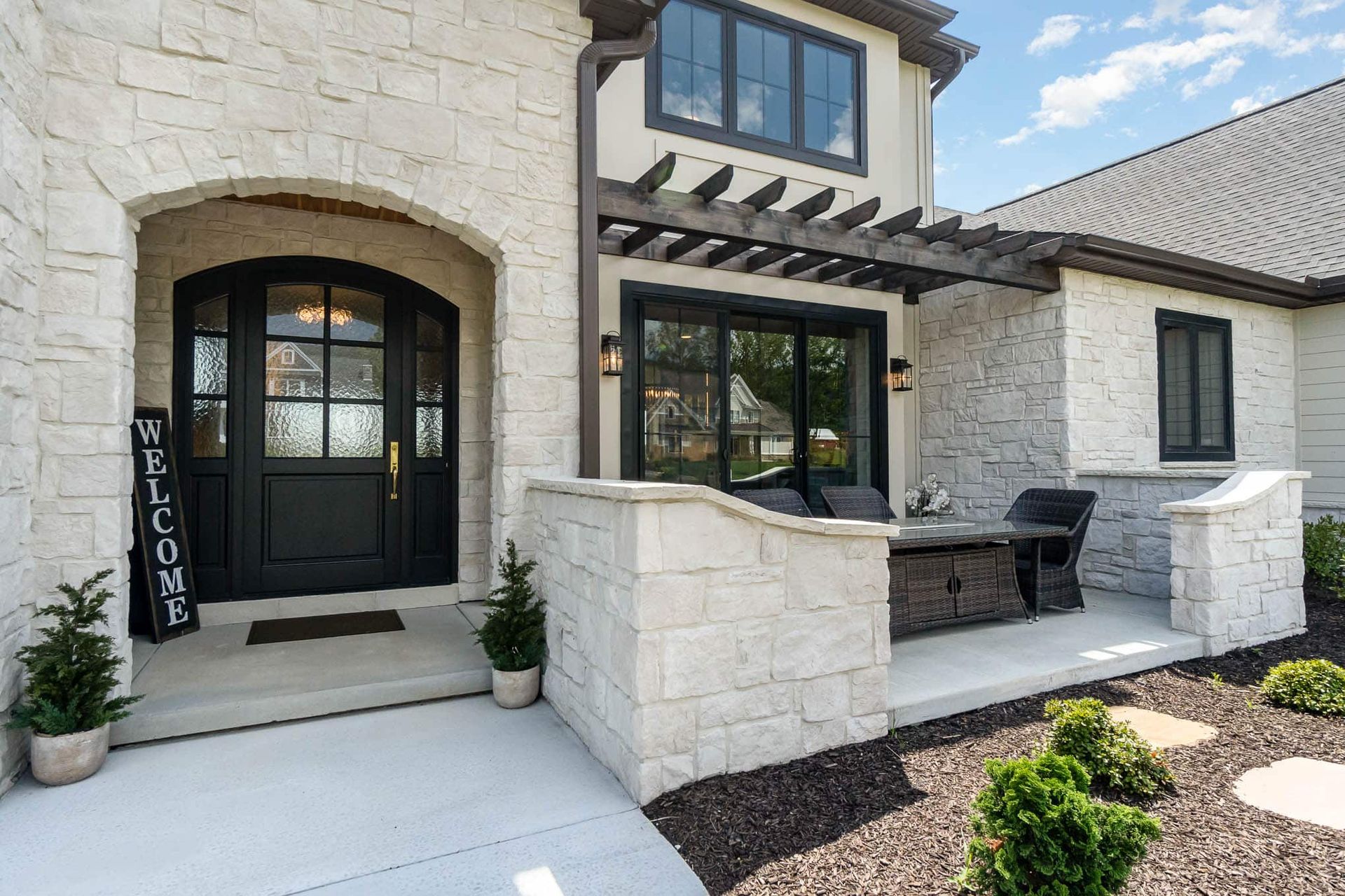 Modern home with black and white exterior, landscaping, and open front door.