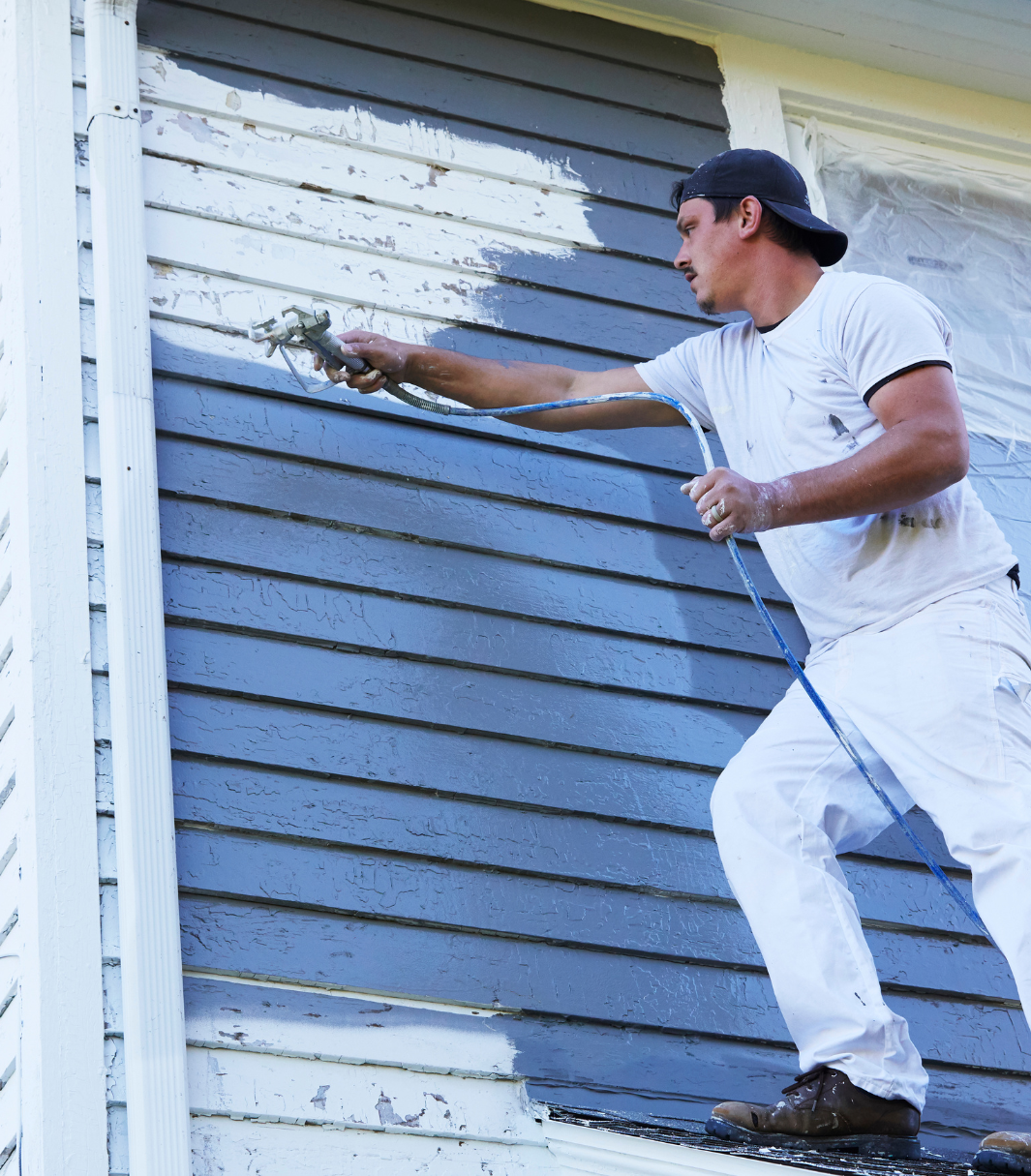 A man is painting the side of a house blue