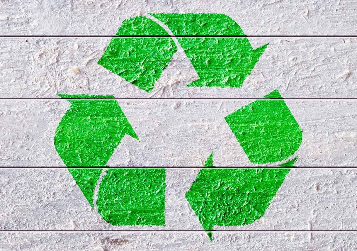 A green recycling symbol is painted on a white wall.