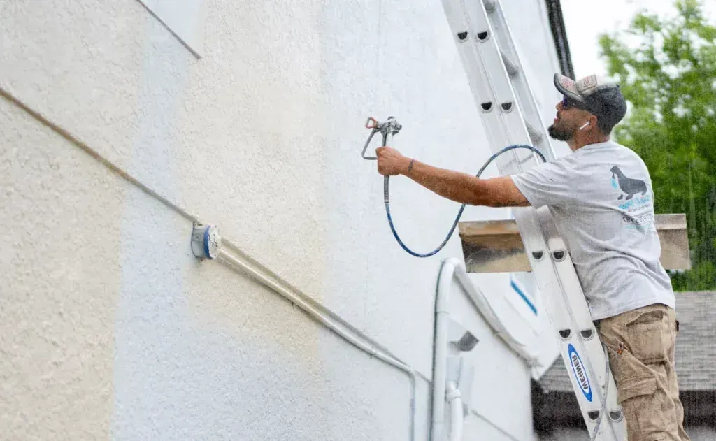 A man is standing on a ladder painting a wall.