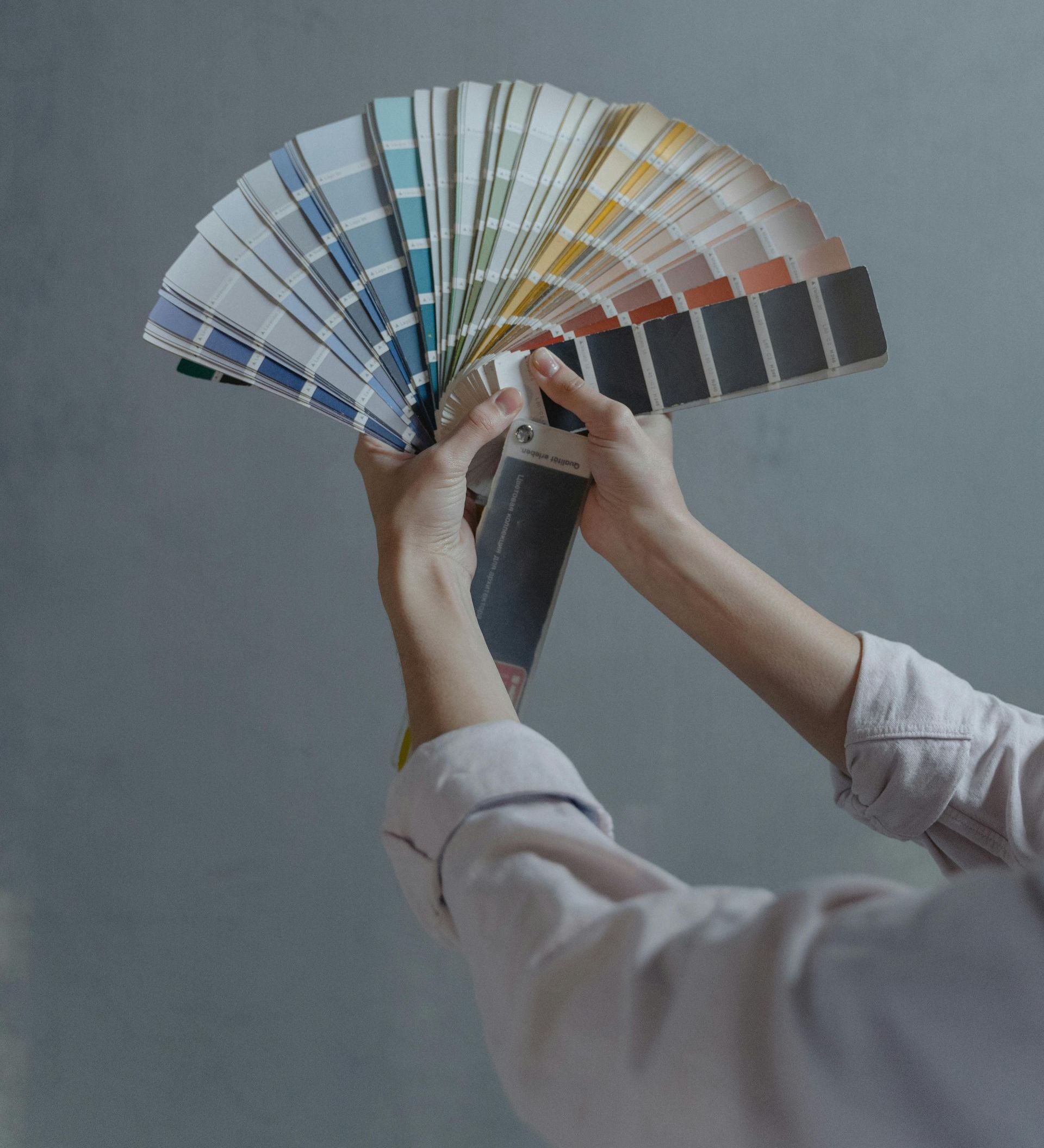 A person is holding a fan of paint samples in their hands
