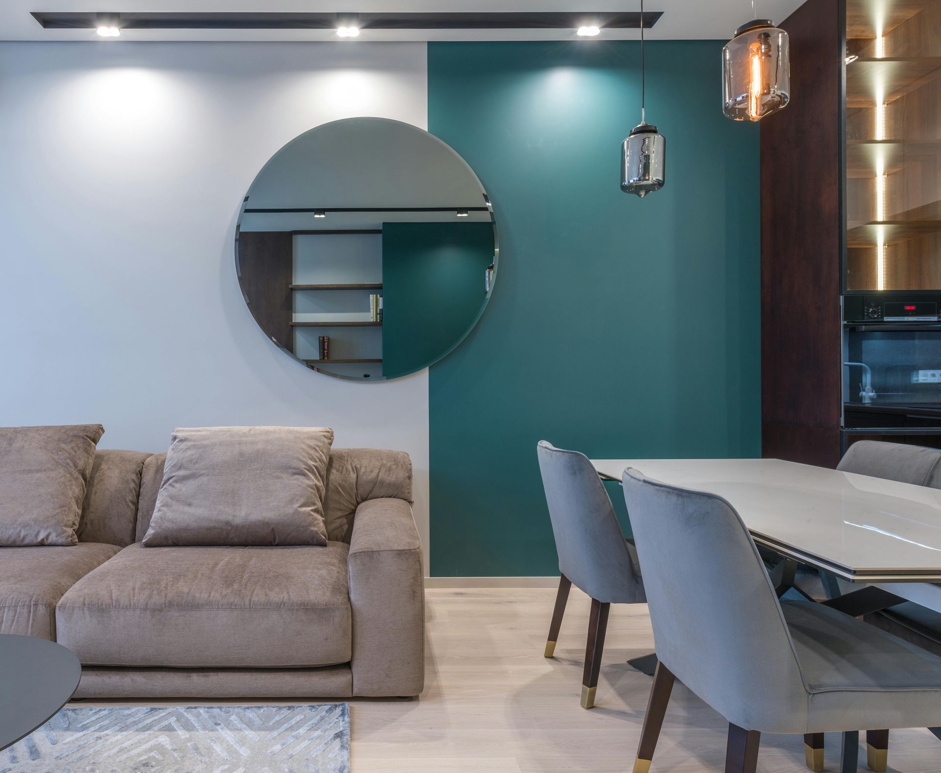 A living room with a couch and a round mirror on the wall