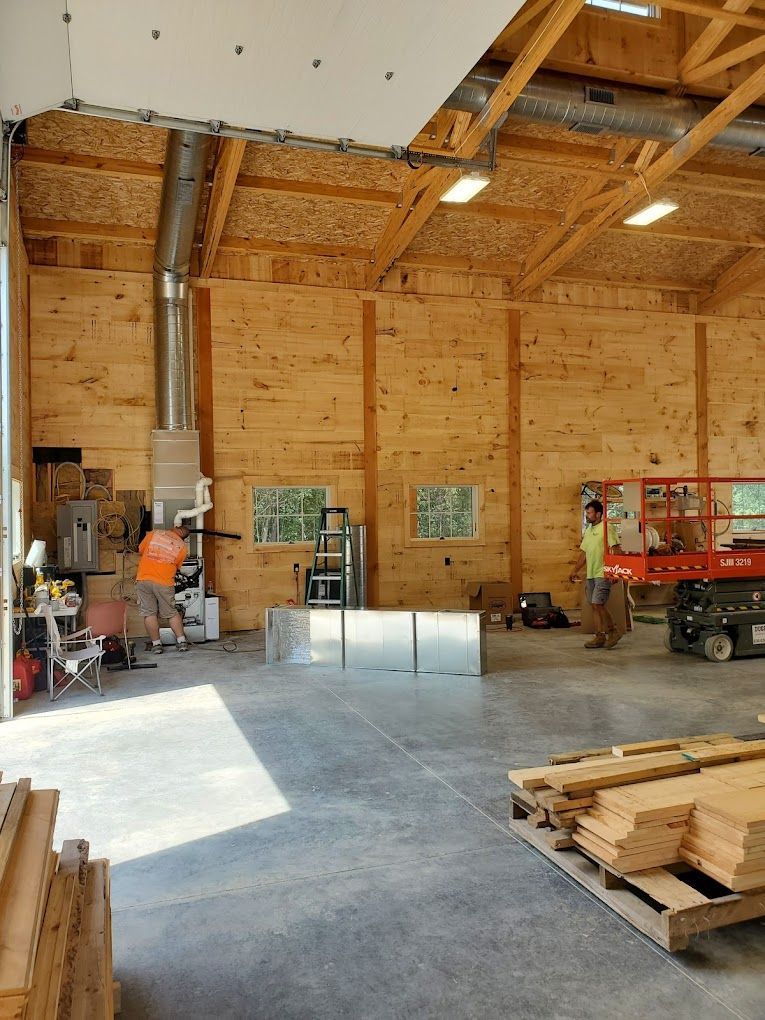 A man is working on installing a new furnace in a large wooden building.