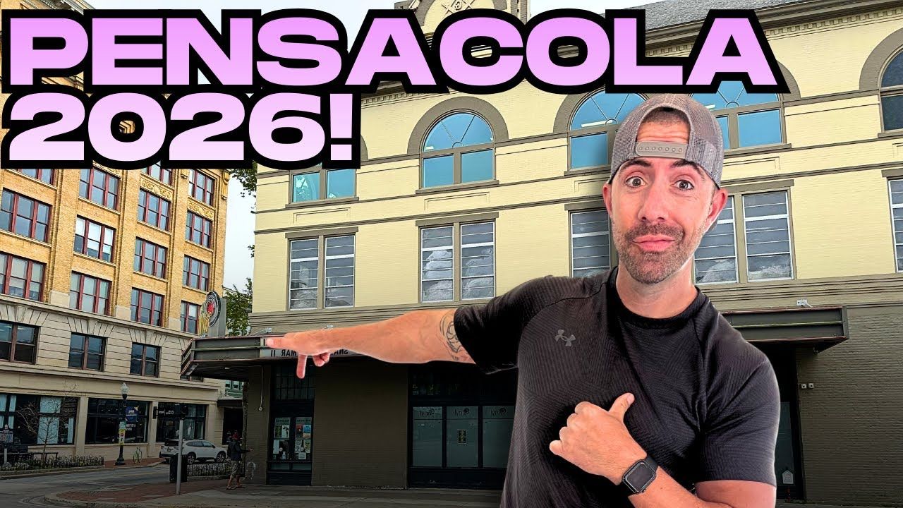 Man pointing at a downtown building with bold purple text reading “PENSACOLA 2026!”