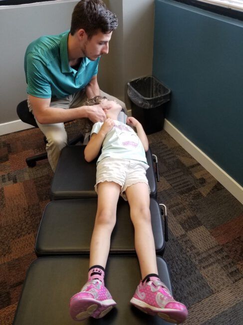 Therapist stretching a child on a treatment table in a clinic room