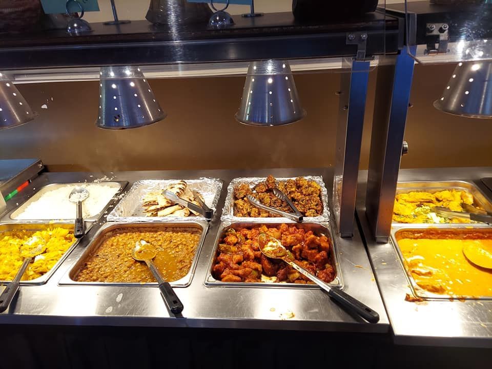 Buffet with various Indian food dishes under warming lamps.