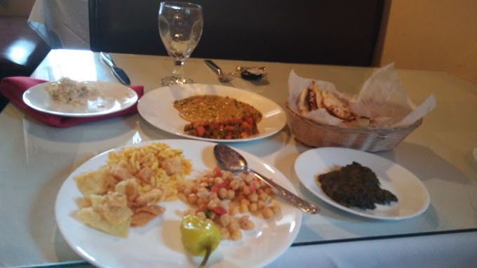 Table setting with plates of food, including rice, bread, and dips. A glass of water is in the background.